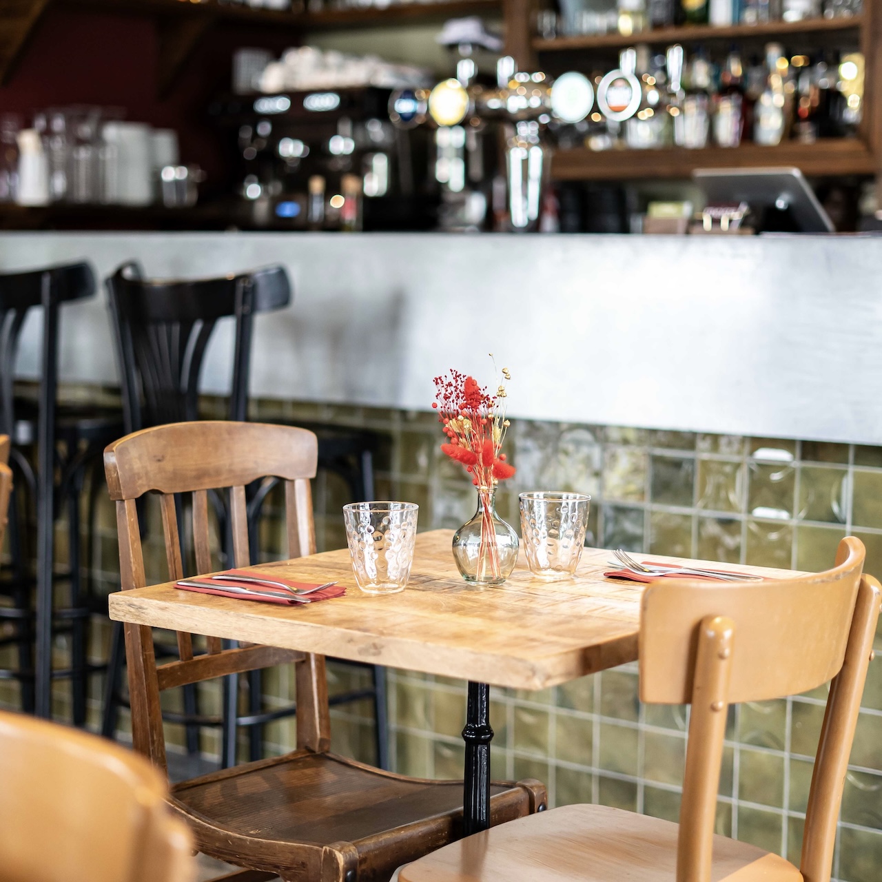 Mobilier ancien chiné avec un bar en faïence en arrière-plan, créant une atmosphère chaleureuse