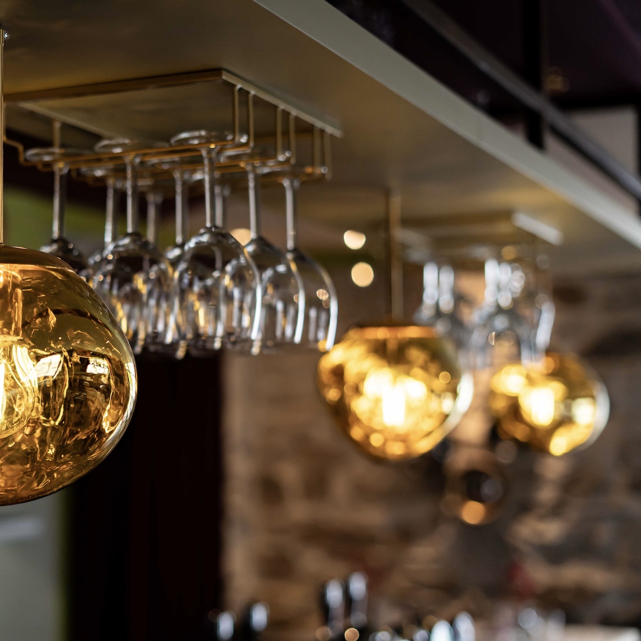 Zoom sur suspensions en verre suspendues au plafond du bar, créant une ambiance mystique et raffinée