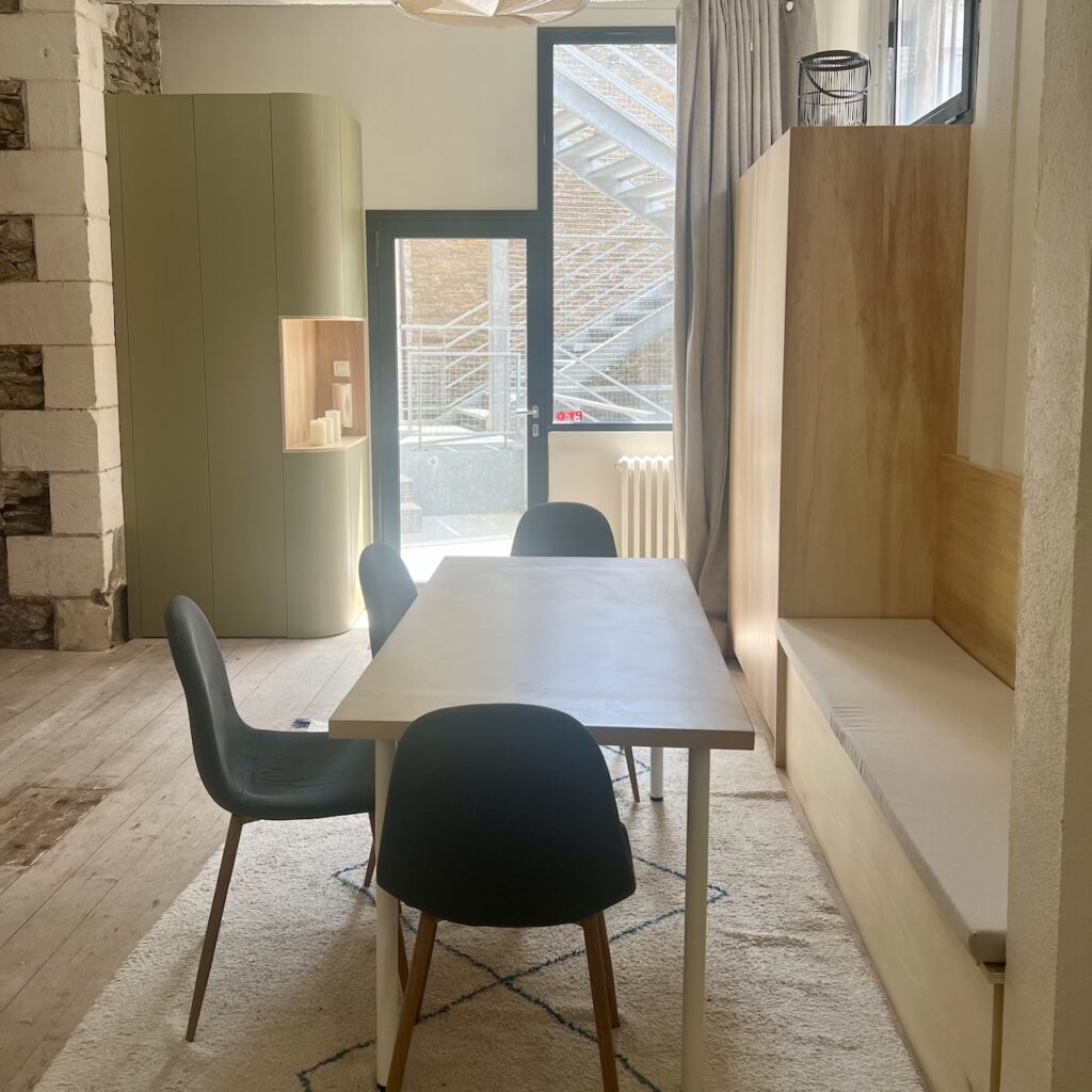 Entrée avec rangement intégré et coin repas avec banquette sur-mesure dans un loft industriel à Nantes