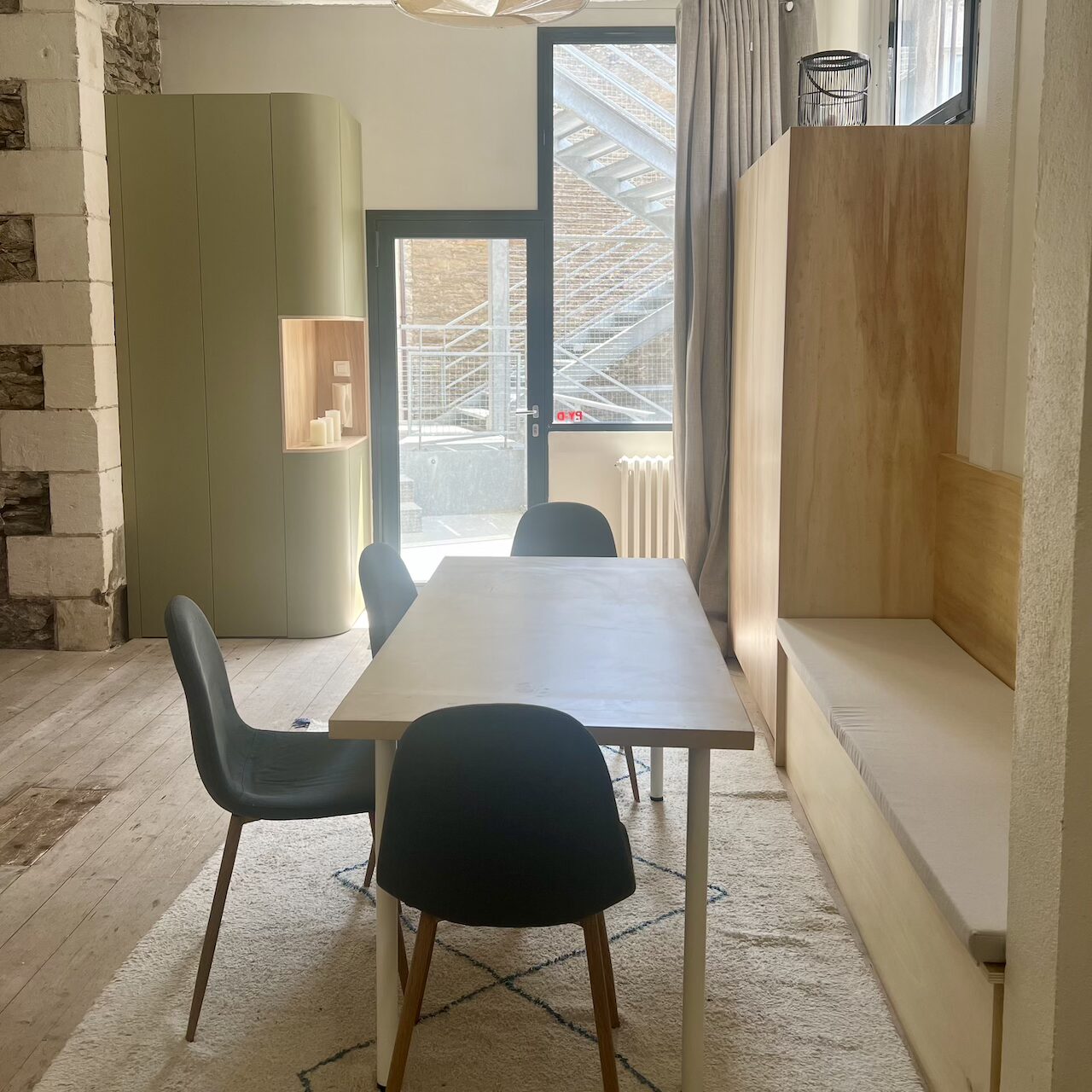 Entrée avec rangement intégré et coin repas avec banquette sur-mesure dans un loft industriel à Nantes