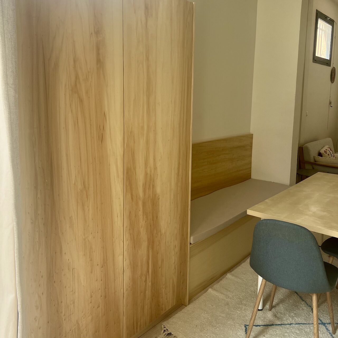 Coin repas avec banquette en contreplaqué, rangement coffre intégré et dressing mural dans un loft à Nantes