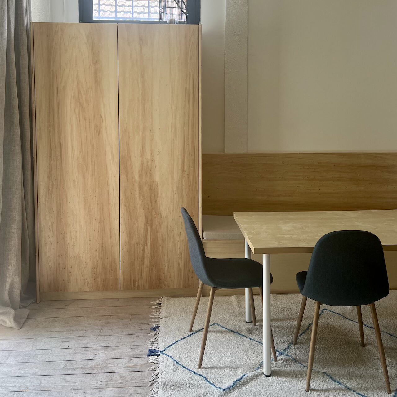 Coin repas avec banquette en contreplaqué, rangement coffre intégré et dressing mural dans un loft à Nantes