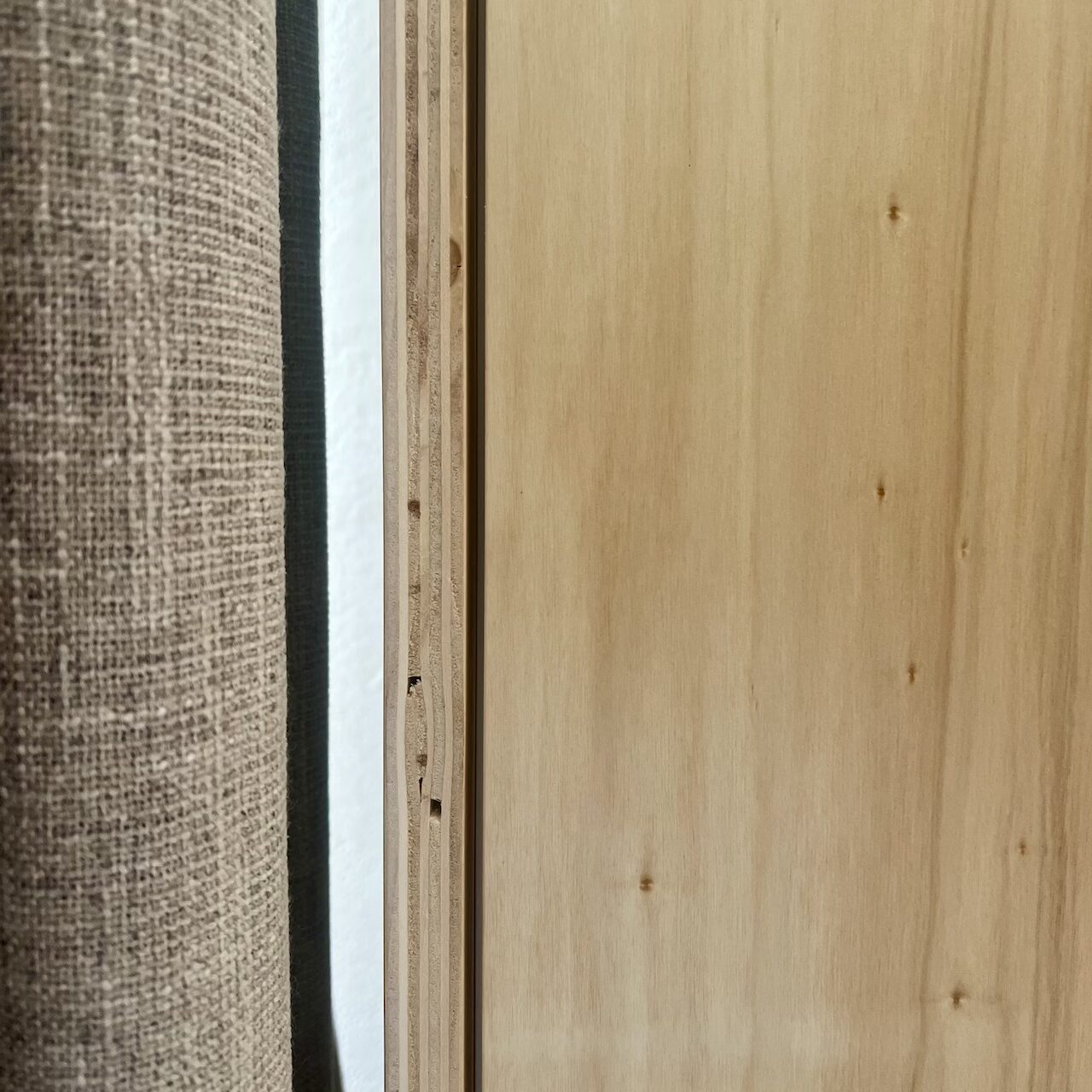 Détail du contreplaqué brut et des rideaux occultants et isolants installés dans un loft industriel à Nantes