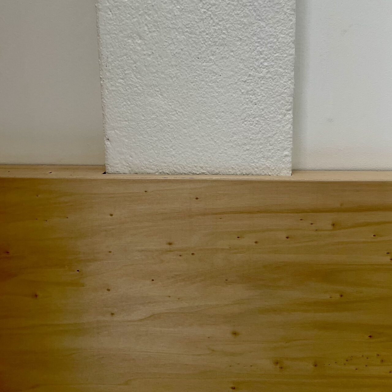 Zoom sur le détail de la banquette en contreplaqué encastrée dans un poteau en béton brut dans un loft nantais