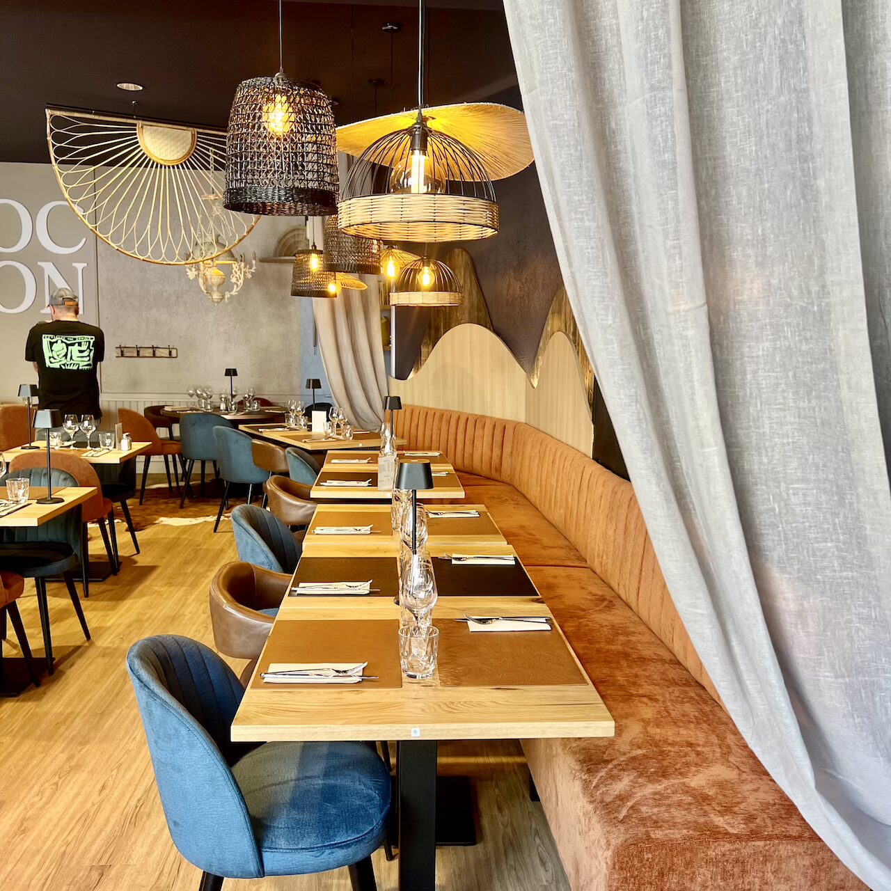 Vue de l’espace restauration avec banquette et un mélange de suspensions au plafond