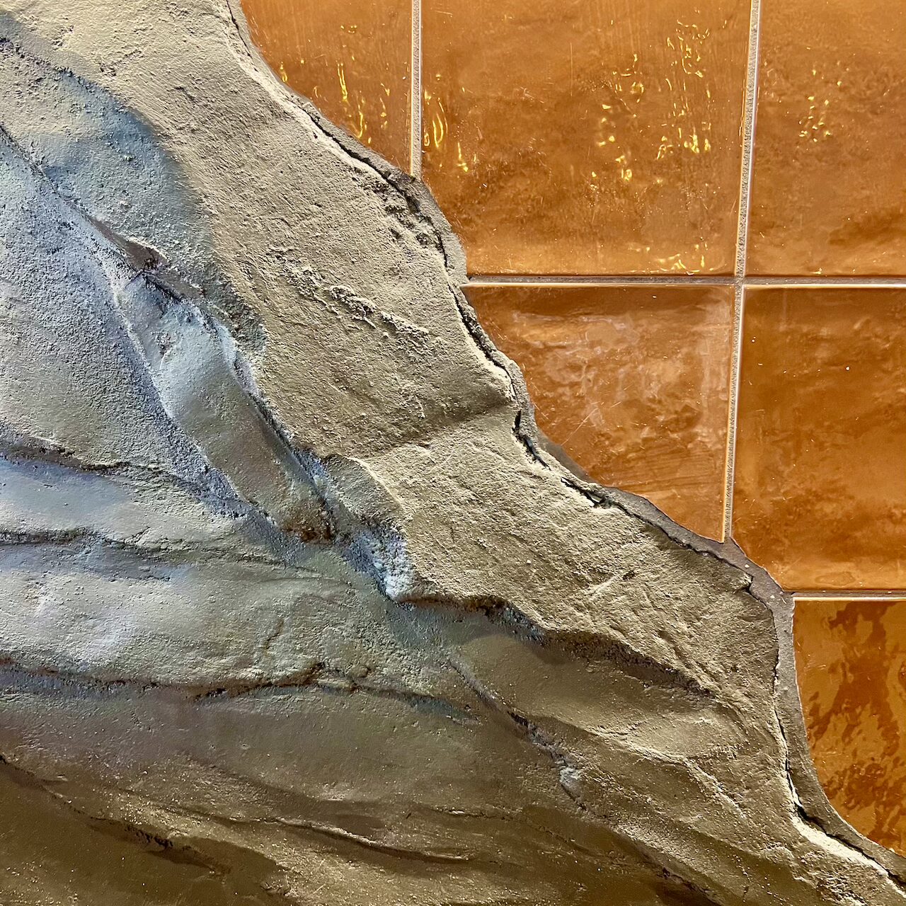 Détail de la texture pierre noire et faïence brune sur l’habillage du bar central