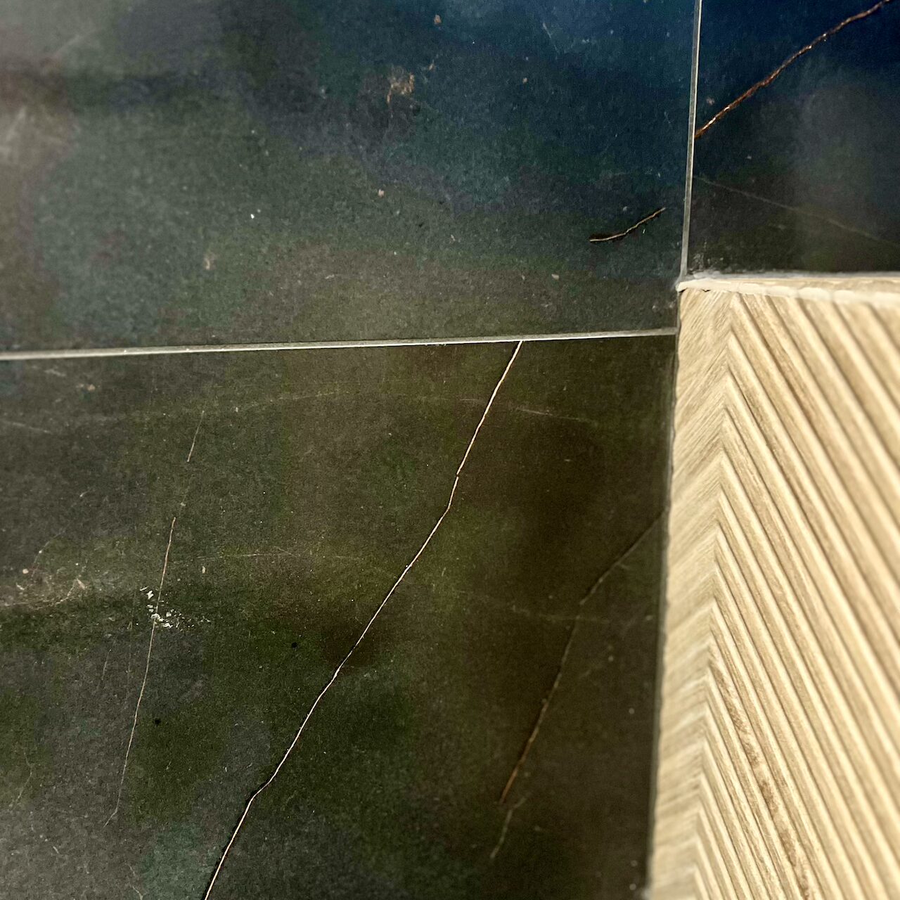 Zoom sur un carrelage effet marbre associé à un revêtement bois dans des WC au design masculin