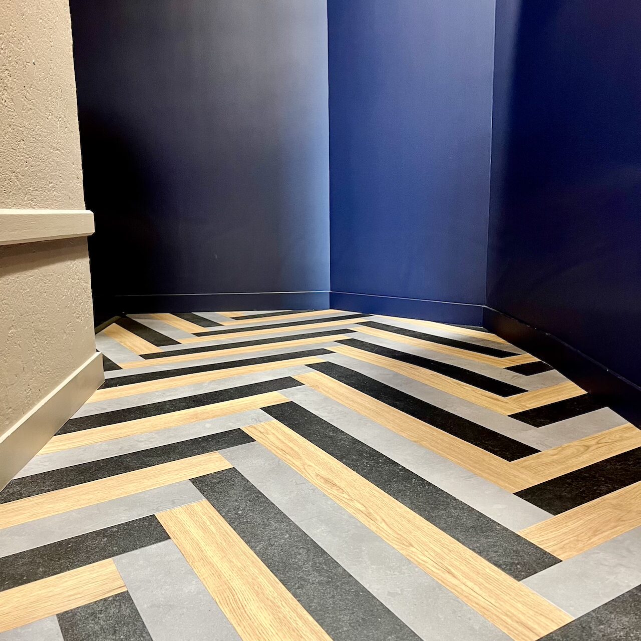 Couloir avec mur bleu profond, sol en parquet chevron et suspensions naturelles suspendues