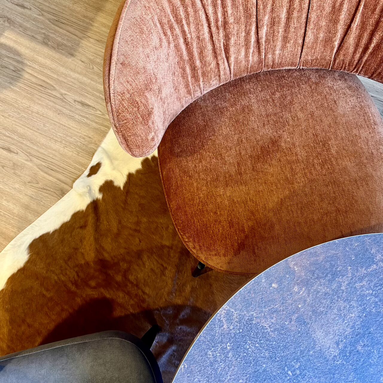 Détail du fauteuil en velours terracotta dans le coin lounge avec tapis contrastant