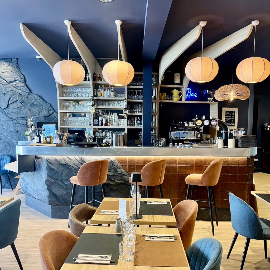 Bar central en pierre noire avec faïence brune, suspensions en tissu en forme de cocons