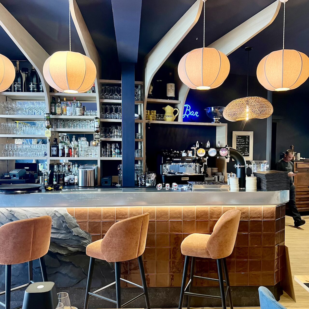 Bar central en pierre noire avec faïence brune, suspensions en tissu en forme de cocons