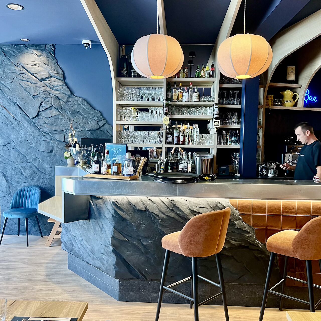 Bar central en pierre noire avec faïence brune, suspensions en tissu en forme de cocons