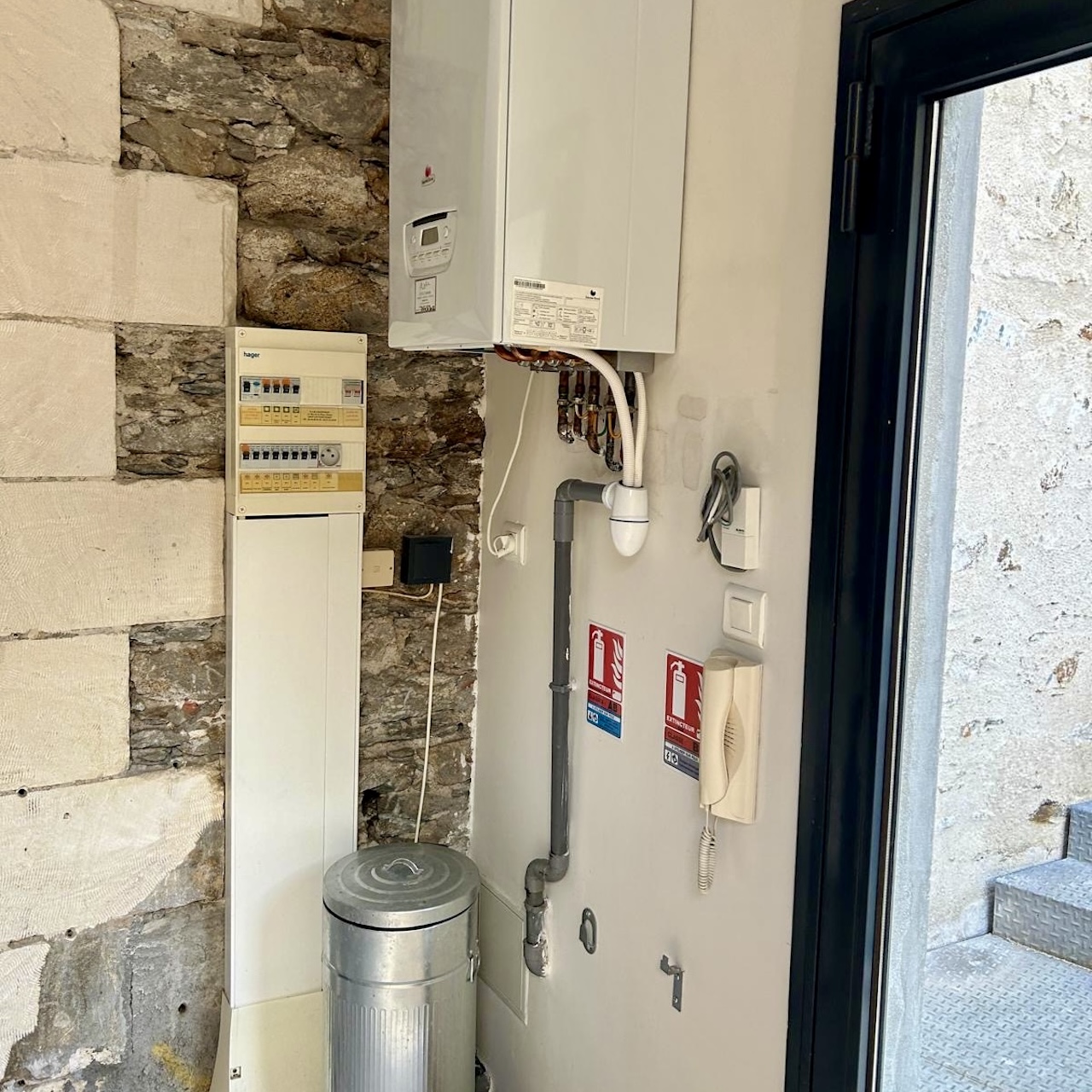 Entrée d’un loft à Nantes avant aménagement, avec disjoncteur apparent, chaudière et aucun rangement