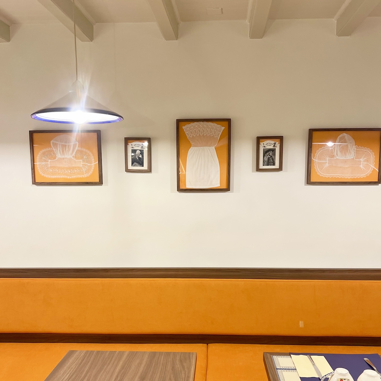 Banquette mandarine dans la salle du fond, accompagnée de tableaux aux tons orangés rappelant l’univers breton.