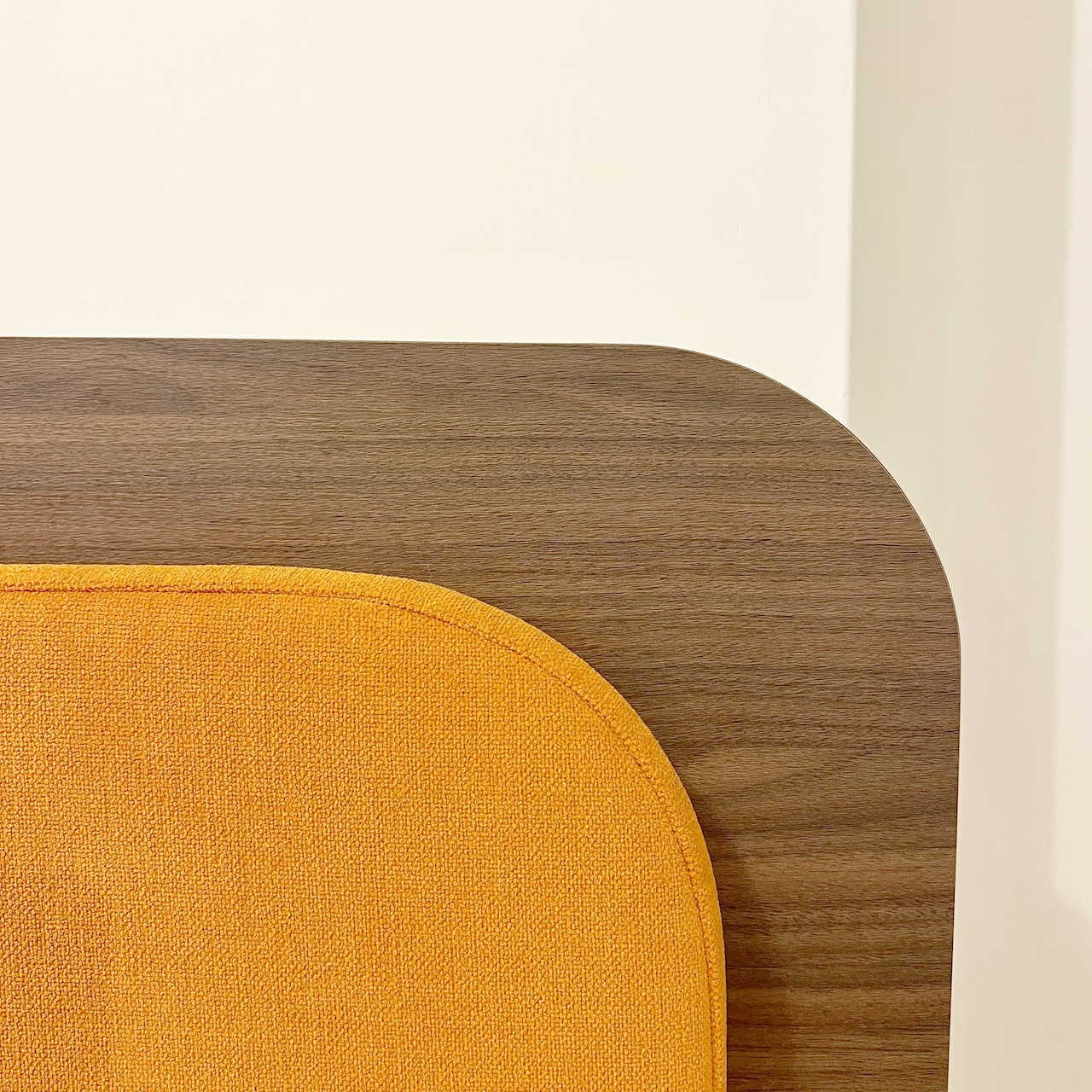 Détail d’une banquette aux consignes en darine et bois sombre, avec des formes arrondies et confortables.