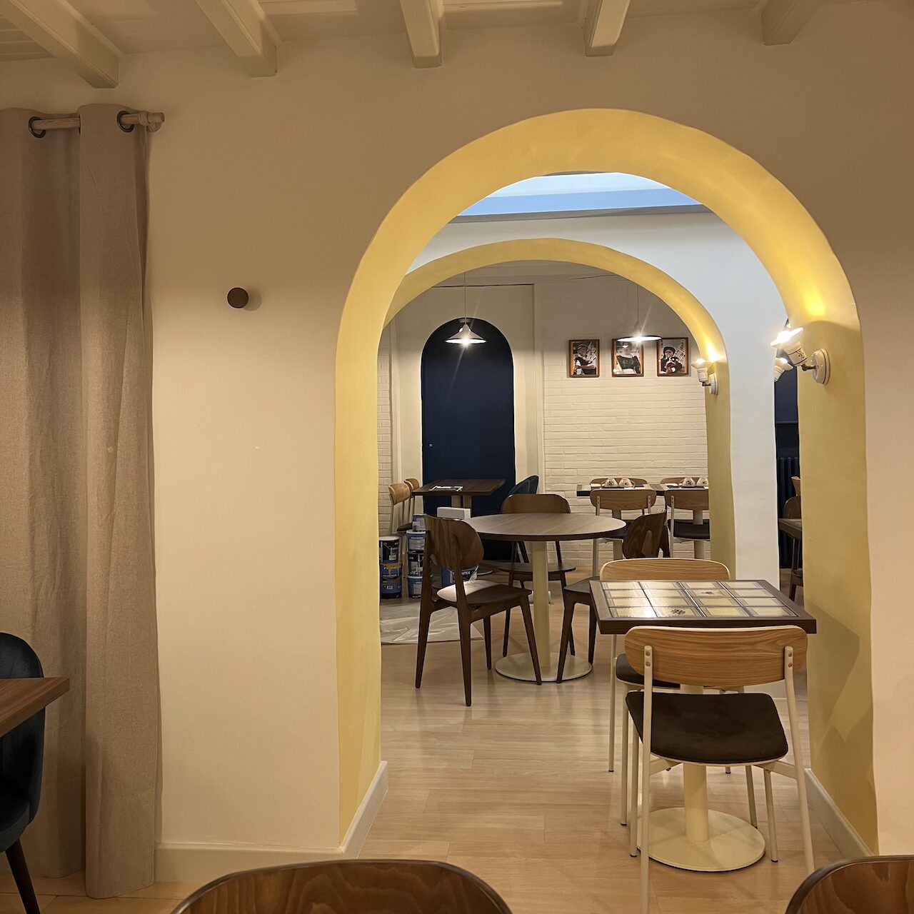 Vue de la salle de restauration du Biniou avec des arches jaunes et blanches en premier plan et des arches bleues en contraste au fond.