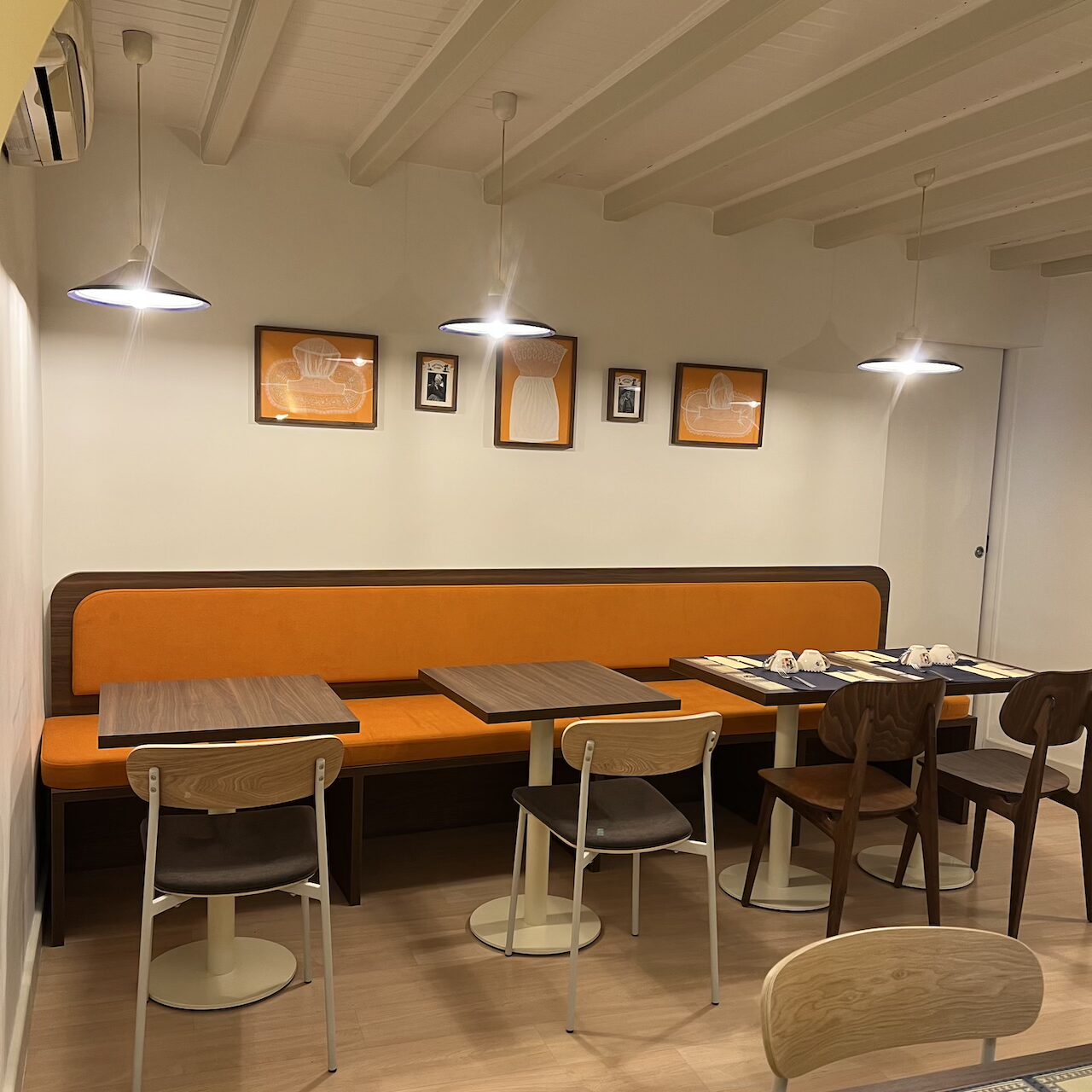 Banquette mandarine dans une salle du fond, éclaircie et rendue lumineuse, avec des cadres en arrière-plan.