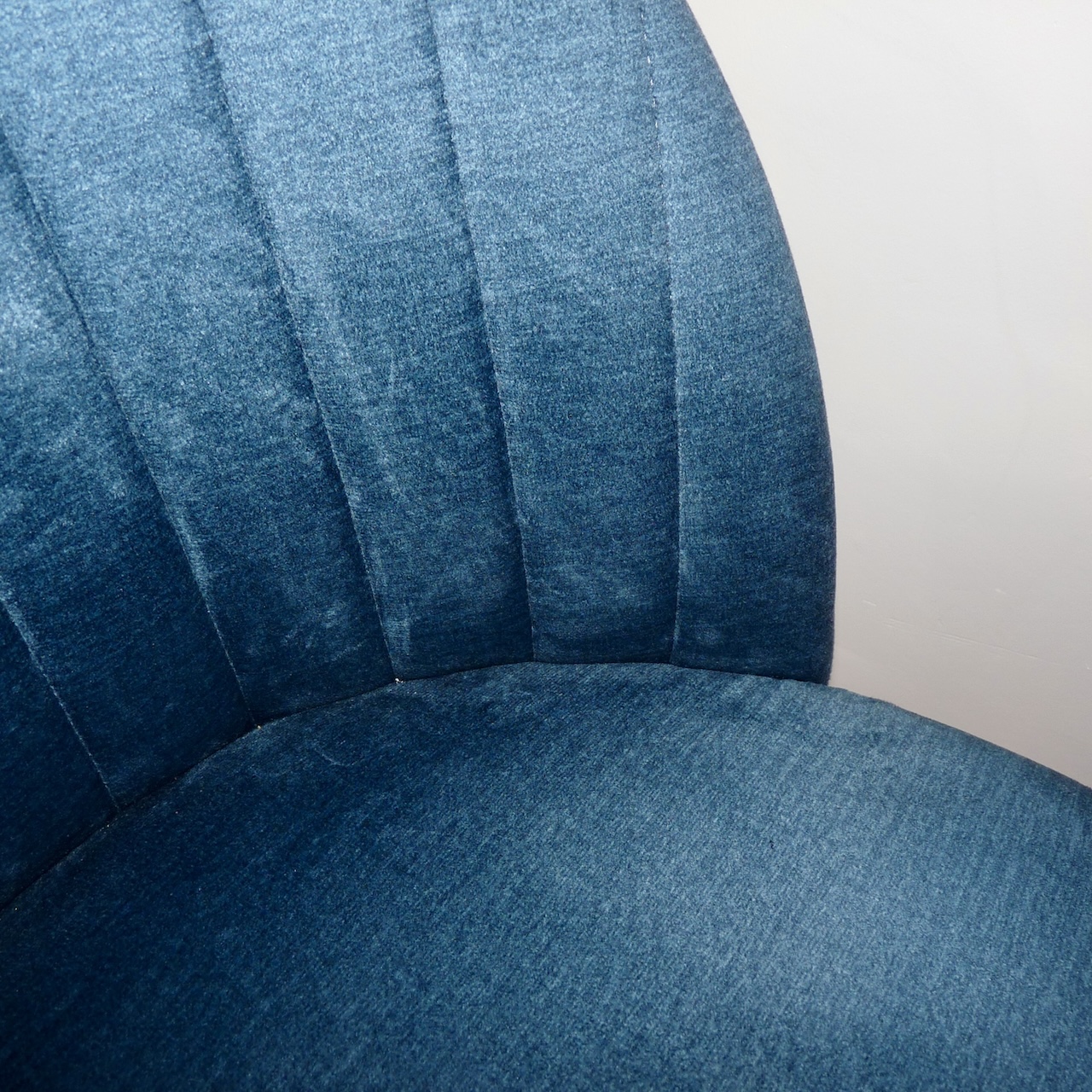 Détail d’un fauteuil en velours bleu, confortable et élégant, intégré au mobilier.