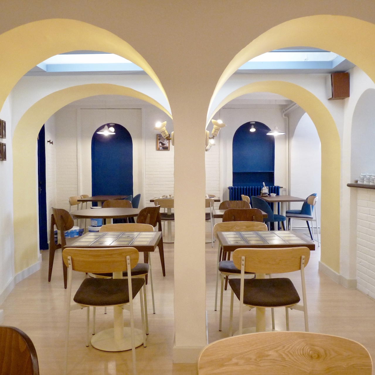 Vue de la salle de restauration du Biniou avec des arches jaunes et blanches en premier plan et des arches bleues en contraste au fond.