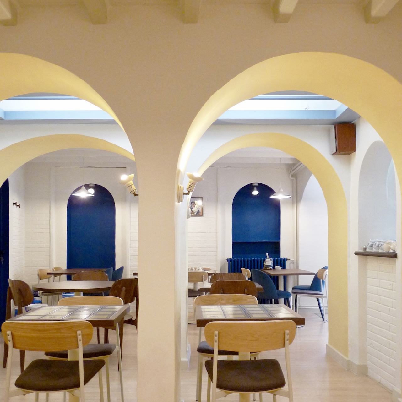 Vue de la salle de restauration du Biniou avec des arches jaunes et blanches en premier plan et des arches bleues en contraste au fond.