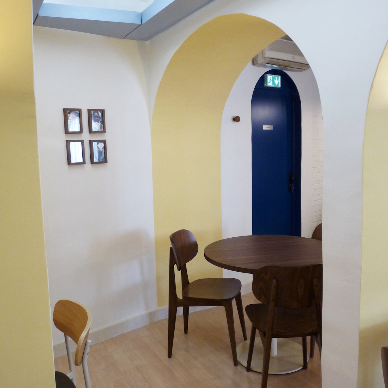 Vue d’une petite partie du restaurant entre quatre arches, avec un plafonnier en bois diffusant une lumière douce et mettant en valeur les courbes et ombres.