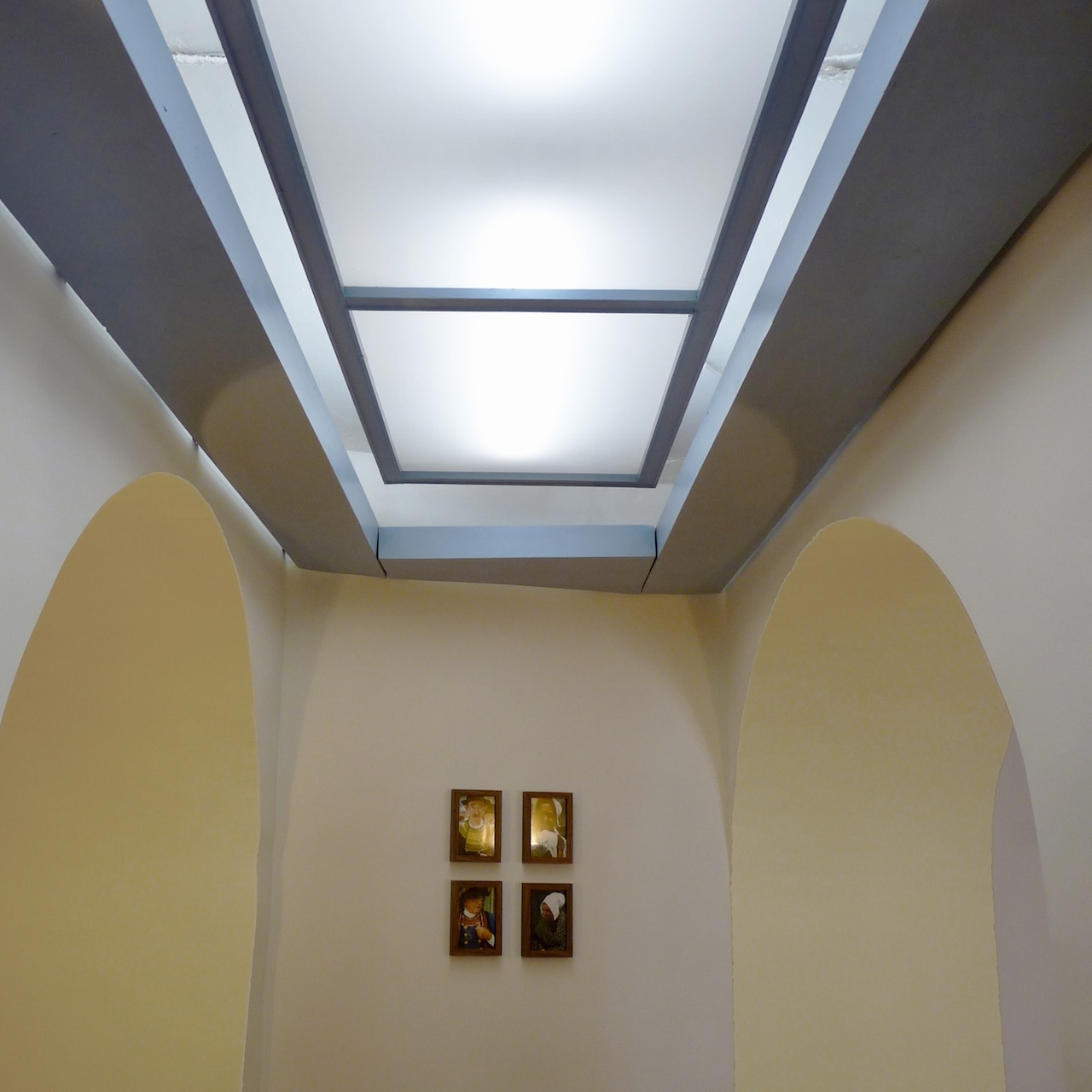 Vue d’une petite partie du restaurant entre quatre arches, avec un plafonnier en bois diffusant une lumière douce et mettant en valeur les courbes et ombres.