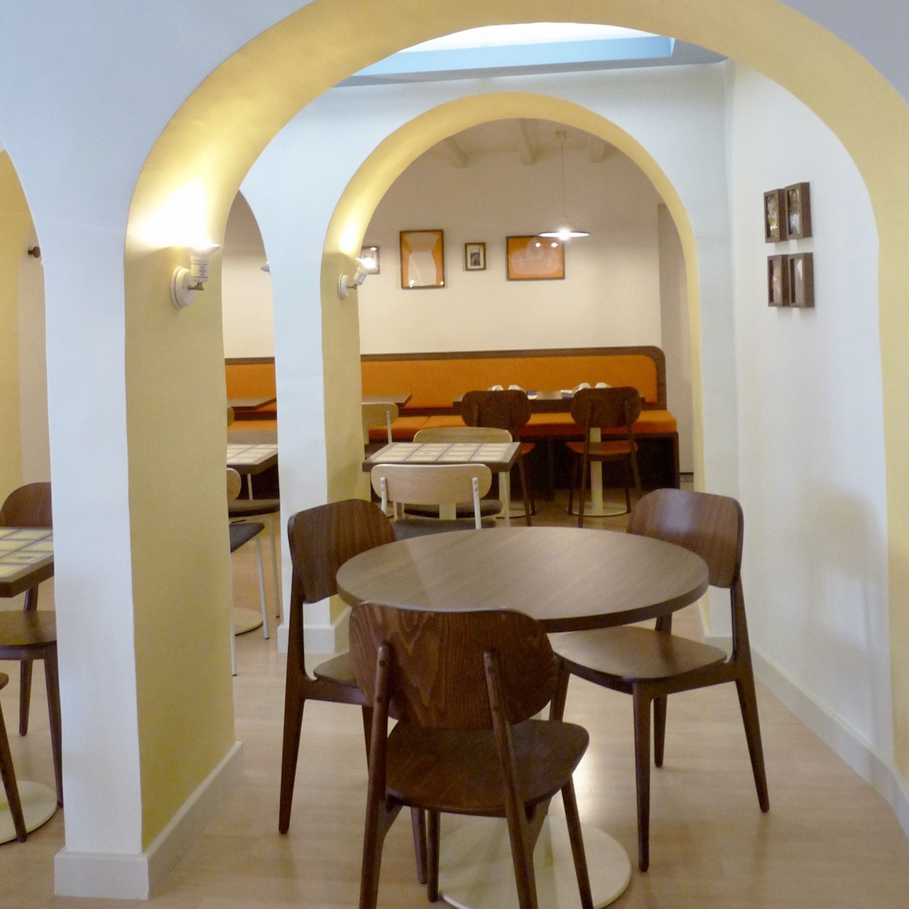 Vue entre les arches vers la salle du fond et sa banquette mandarine