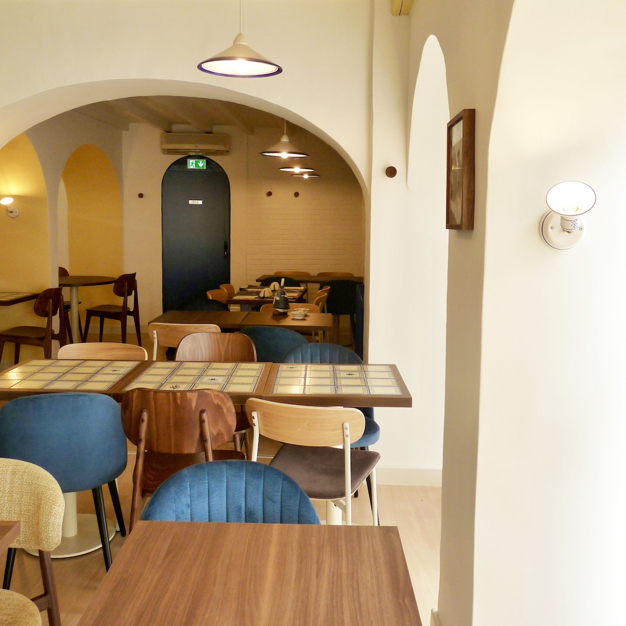 Vue de la salle de restauration du Biniou avec des arches jaunes et blanches en premier plan et des arches bleues en contraste au fond.
