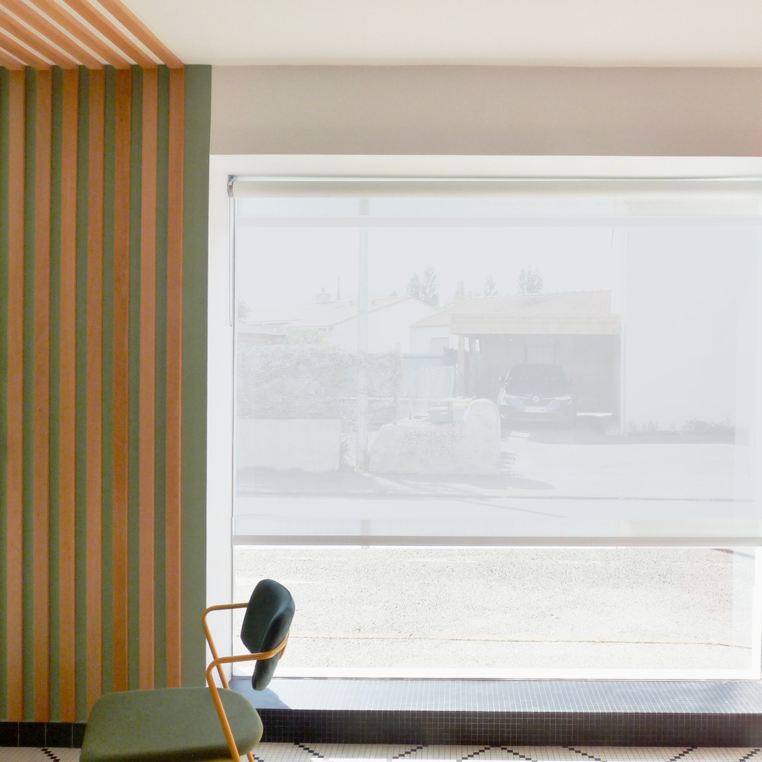 Vue de l’espace vert du showroom avec tasseaux bois et grande baie vitrée donnant sur la rue, apportant visibilité et lumière naturelle.