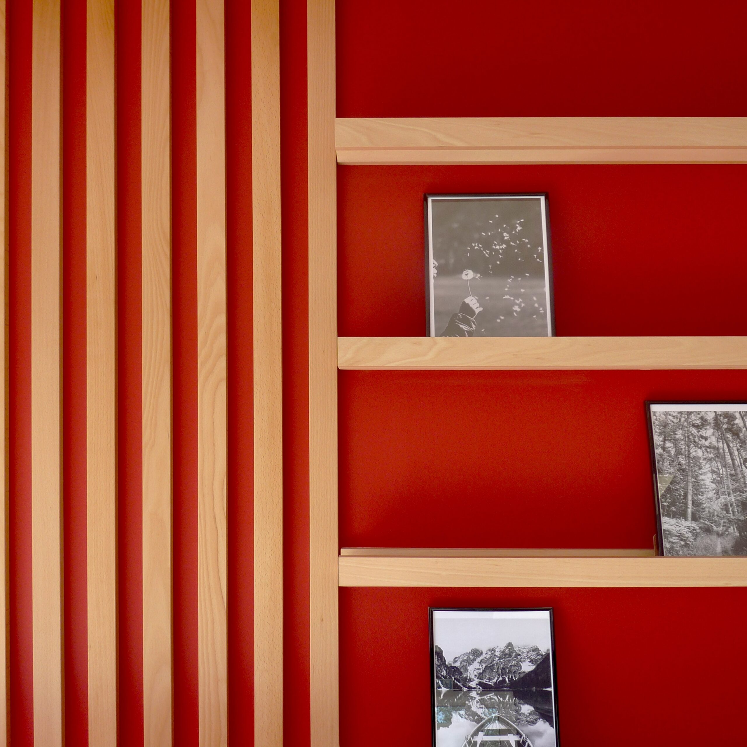 Showroom aménagé avec un mur rouge, des tasseaux en bois et une tablette pour documents commerciaux réalisés pour un artisan.